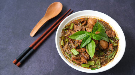 Thai style noodle soup with pork and green basil in a bowl on black backgroundの写真素材