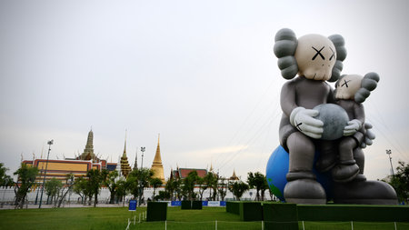 May 22 2025, Bangkok, Thailand : Tourist gather at Sanam Luang where a giant KAWS inflatable sculpture stand against the backdrop of Grand Palace's iconic Thai architecture.の写真素材