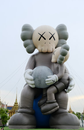 May 22 2025, Bangkok, Thailand : Tourist gather at Sanam Luang where a giant KAWS inflatable sculpture stand against the backdrop of Grand Palace's iconic Thai architecture.の写真素材