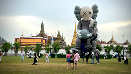 May 22 2025, Bangkok, Thailand : Tourist gather at Sanam Luang where a giant KAWS inflatable sculpture stand against the backdrop of Grand Palace's iconic Thai architecture.の写真素材