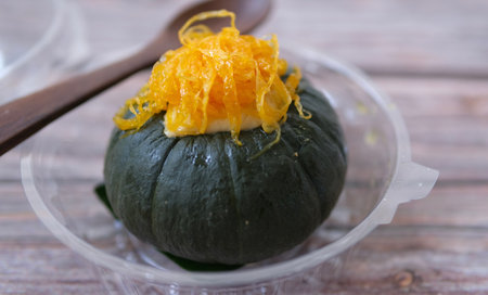 steamed pumpkin stuffed with egg custard isolated on wooden background, Thai traditional dessertの写真素材