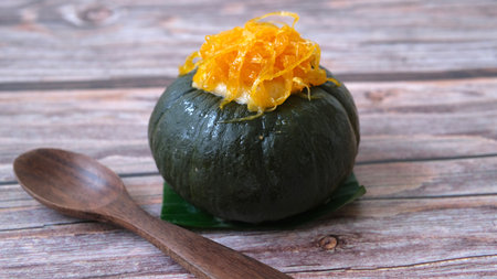 steamed pumpkin stuffed with egg custard isolated on wooden background, Thai traditional dessertの写真素材