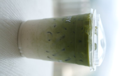Iced matcha latte in a plastic cup, blurred background