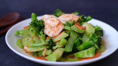 table top view stir-fried broccoli with shrimp and carrot in white plate isolated on black background.の写真素材