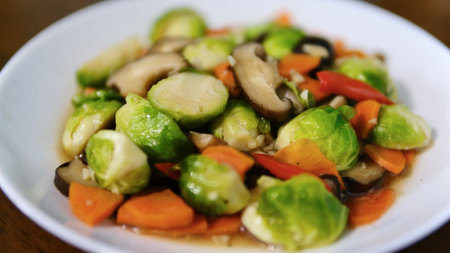 Stir fried Brussels sprouts with mushrooms and carrots on white plate, selective focusの写真素材
