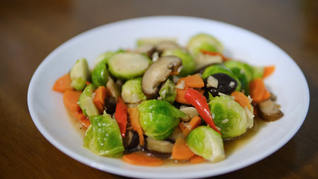 Stir fried Brussels sprouts with mushrooms and carrots on white plate, selective focusの写真素材
