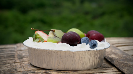 Fresh fruit cake with whipped cream in a bowl on wooden table. Selective focusの写真素材