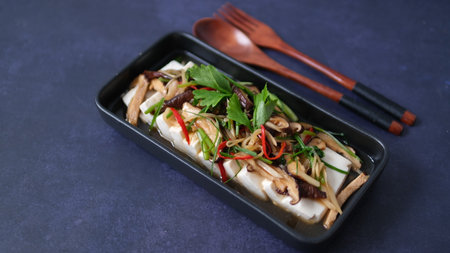 Steamed tofu with with mushroom and vegetable in soy sauce on black backgroundの写真素材