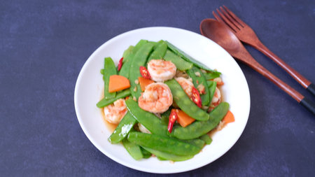 Stir-fried snow peas with shrimp and chili isolated on black backgroundの写真素材