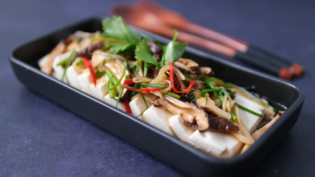 Steamed tofu with mushroom and vegetable in soy sauce on black backgroundの写真素材