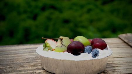 Fresh fruit cake with whipped cream in a bowl on wooden table. Selective focusの写真素材