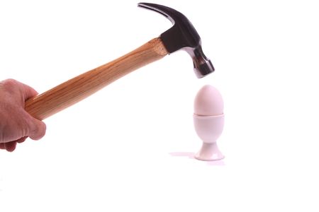 Hand with hammer reaching out voor an egg on a withe isolated background with copy spaceの写真素材