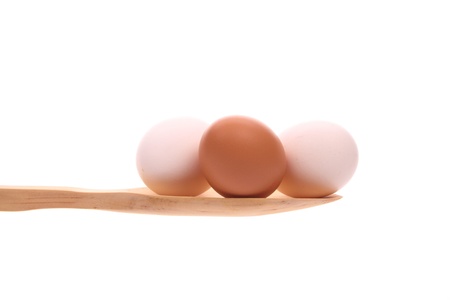 Eggs simply offered on a wooden spoon isolated on a white background の写真素材