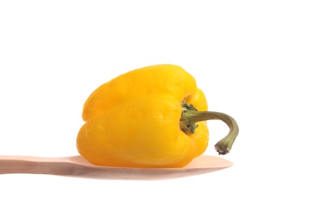 Old bell pepper simply offered on a wooden spoon isolated on a white background の写真素材