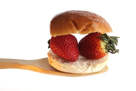 Strawberries on a bread roll wooden spoon against a white backgroundの写真素材