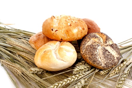 Various bread rolls on grain against a white background