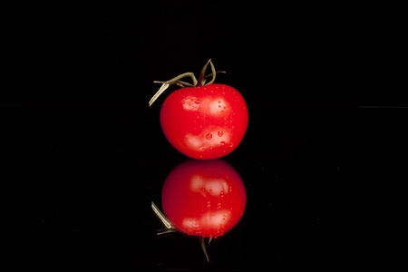 Fresh tomato against a black background in a studio settingの写真素材