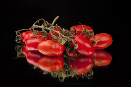 Fresh tomatos against a black background in a studio settingの写真素材