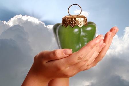 Young womans hand showing a bell pepper with  bauble capの写真素材