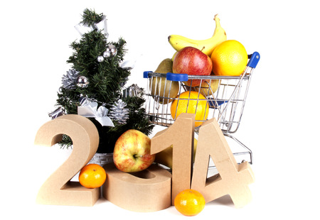 Some fruits in a mini shopping cart against a white background