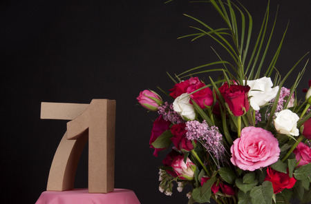 Age in figures next to a bouquet of flowers on a black backgroundの写真素材