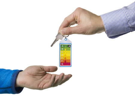 Realtor handing over the key with energy label to a new home owner on a white backgroundの写真素材