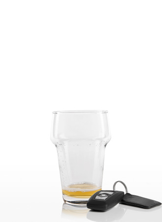 Empty beer glass next to car keys on a white backgroundの写真素材