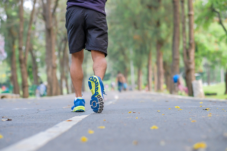 young fitness man legs walking in the park outdoor, male runner running on the road outside, asian athlete jogging and exercise on footpath in sunlight morning. Sport,healthy and wellness conceptsの写真素材