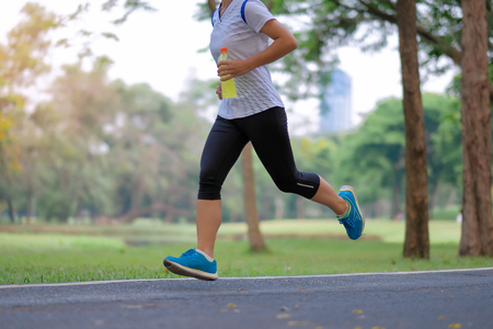 young fitness woman legs walking in the park outdoor, female runner running on the road outside, asian athlete jogging and exercise on footpath in sunlight morning. Sport,healthy and wellness conceptsの写真素材