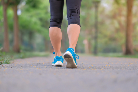 young fitness woman legs walking in the park outdoor, female runner running on the road outside, asian athlete jogging and exercise on footpath in sunlight morning. Sport,healthy and wellness conceptsの写真素材