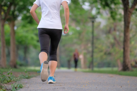 young fitness woman legs walking in the park outdoor, female runner running on the road outside, asian athlete jogging and exercise on footpath in sunlight morning. Sport,healthy and wellness conceptsの写真素材