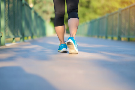 young fitness woman legs walking in the park outdoor, female runner running on the road outside, asian athlete jogging and exercise on footpath in sunlight morning. Sport,healthy and wellness conceptsの写真素材