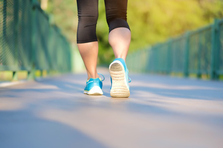 young fitness woman legs walking in the park outdoor, female runner running on the road outside, asian athlete jogging and exercise on footpath in sunlight morning. Sport,healthy and wellness conceptsの写真素材