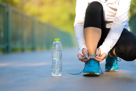Young athlete woman tying running shoes in the park outdoor, female runner ready for jogging on the road outside, asian Fitness walking and exercise on footpath in morning. wellness and sport conceptsの写真素材