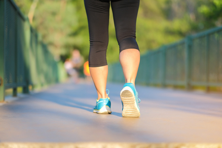 young fitness woman legs walking in the park outdoor, female runner running on the road outside, asian athlete jogging and exercise on footpath in sunlight morning. Sport,healthy and wellness conceptsの写真素材