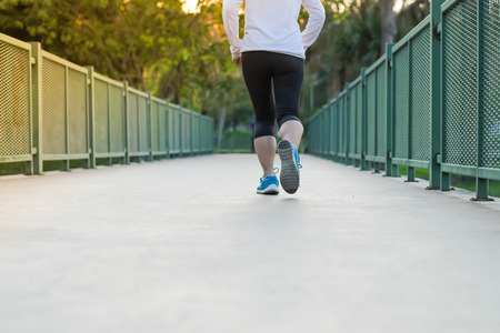 young fitness woman legs walking in the park outdoor, female runner running on the road outside, asian athlete jogging and exercise on footpath in sunlight morning. Sport,healthy and wellness conceptsの写真素材