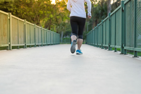 young fitness woman legs walking in the park outdoor, female runner running on the road outside, asian athlete jogging and exercise on footpath in sunlight morning. Sport,healthy and wellness conceptsの写真素材