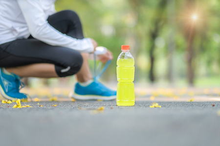 Young athlete woman tying running shoes in the park outdoor, female runner ready for jogging on the road outside, asian Fitness walking and exercise on footpath in morning. wellness and sport conceptsの写真素材