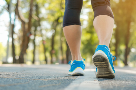 young fitness woman legs walking in the park outdoor, female runner running on the road outside, asian athlete jogging and exercise on footpath in sunlight morning. Sport,healthy and wellness conceptsの写真素材