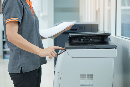Bussiness woman Hand press button on panel of printer scanner or laser copy machine in officeの写真素材