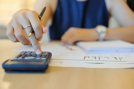 Businesswoman using calculator for analysis maketing plan, Accountant calculate financial report, computer with graph chart.  Business, Finance and Accounting conceptsの写真素材