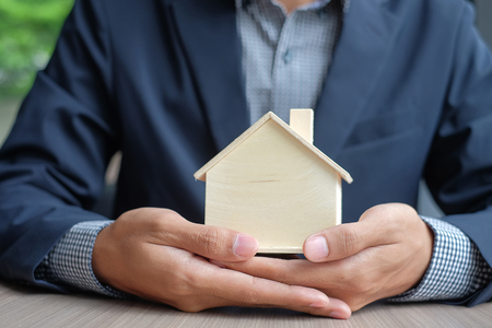 Businessman hands holding wooden House model. Property insurance and real estate conceptsの写真素材
