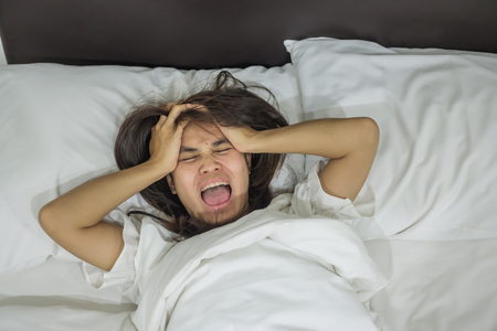 Asian woman lying in bed late at night, young female sleep in bedroom at home. insomnia sleeping, worried and stressed conceptsの写真素材