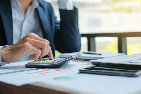 Businessman using calculator for analysis maketing plan, Accountant calculate financial report, computer with graph chart.  Business, Finance and Accounting conceptsの写真素材
