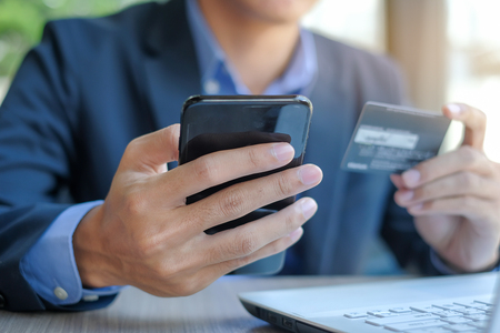 Businessman holding credit card and using smartphone for online shopping while making orders via the Internet. business, technology, ecommerce and online payment conceptの写真素材