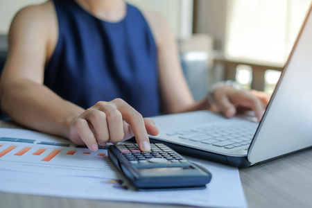 Businesswoman using calculator for analysis maketing plan, Manager calculate financial report and graph chart.  Business, Finance and Accounting conceptsの写真素材