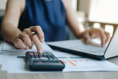 Businesswoman using calculator for analysis maketing plan, Manager calculate financial report and graph chart.  Business, Finance and Accounting conceptsの写真素材
