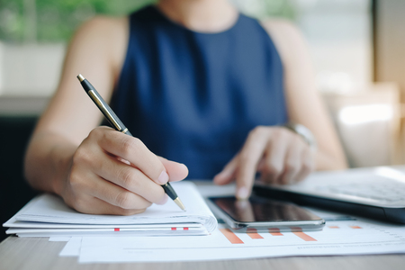Businesswoman using smatphone for analysis maketing plan, Manager calculate financial report and graph chart.  Business, Finance and Accounting conceptsの写真素材