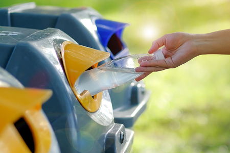Woman Hand throwing plastic water bottle in recycle binの写真素材