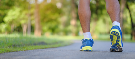young fitness man legs running in the park outdoor, male runner walking on the road outside, asian athlete jogging and exercise on footpath in sunlight morning. Sport, healthy and wellness conceptsの写真素材